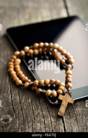 Holz Rosenkranz mit Tablet-Computer auf alten Holztisch Stockfoto