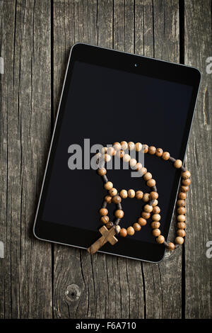 Holz Rosenkranz mit Tablet-Computer auf alten Holztisch Stockfoto