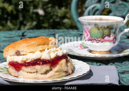 Eine frische Scones mit Schlagsahne Cornish Clotted Cream und Erdbeermarmelade gefüllt auf verzierte antike Porzellan Geschirr serviert Stockfoto