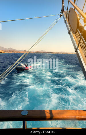 Hölzerne Segelschiff schleppt Schlauchboot im Meer Stockfoto