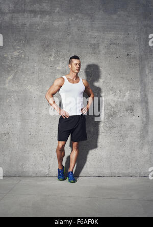 Ganzkörper-Fitness-Porträt von muskulöser Mann, stehen mit beiden die Hände auf seine Taille wegsehen