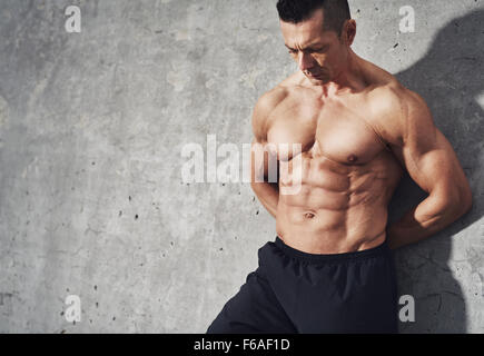 Schließen Sie herauf Bild der Männer in kurzen Hosen entspannend nach Training auf grauem Hintergrund. Muskulöse männliche Körper vor Schweiß. Bild mit Exemplar Stockfoto