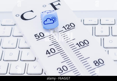 Bild zeigt einen Thermometer mit Würfel auf einer Tastatur Stockfoto