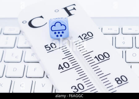 Bild zeigt einen Thermometer mit Würfel auf einer Tastatur Stockfoto