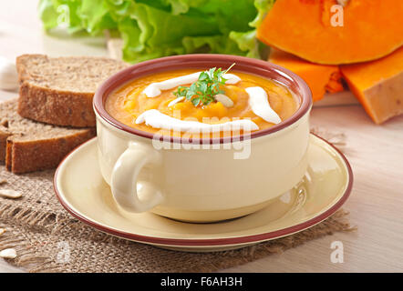 Lecker Sahne Kürbis Suppe in eine Schüssel auf Holztisch Stockfoto
