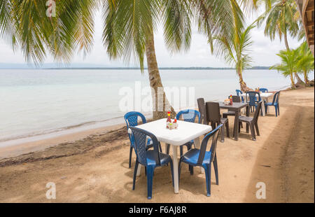 Restauranttische unter den Palmen am Strand Stockfoto