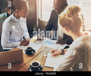 Geschäftsleute über die Tabellen und Grafiken zeigen die Ergebnisse ihrer erfolgreichen Teamarbeit, multi-ethnische Business Stockfoto