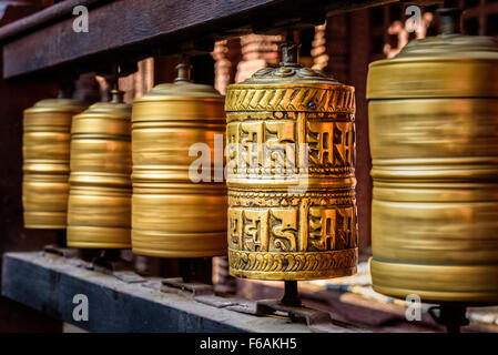 Goldene tibetische Gebetsmühlen in einem buddhistischen Tempel in Nepal Stockfoto
