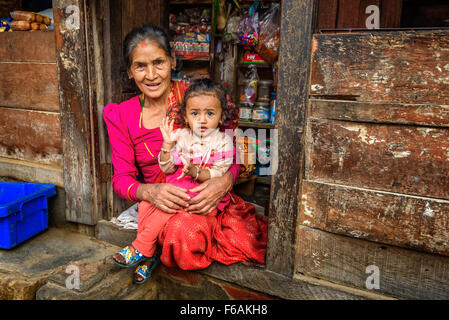 Waren in ihrem Laden verkauft alte nepalesische Frau mit einem Kind. Stockfoto
