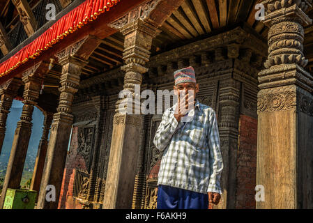 Alte buddhistische Mönch qualmender Zigarette in seinem Tempel in Kathmandu Stockfoto