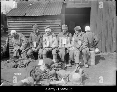 Dieses historische Foto zeigt verwundete deutsche Gefangene in Louvencourt, Frankreich während des Ersten Weltkriegs. Das Bild spiegelt die harten Realitäten des Krieges wider und fängt Soldaten in einem verwundbaren Moment inmitten der Zerstörung des Konflikts ein. Stockfoto