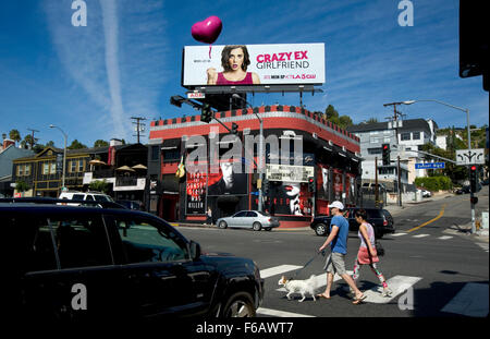 Paare, die auf dem Sunset Strip in der Nähe des Whisky A Go Go Nachtclub mit einer bunten Plakatwand in West Hollywood. Stockfoto