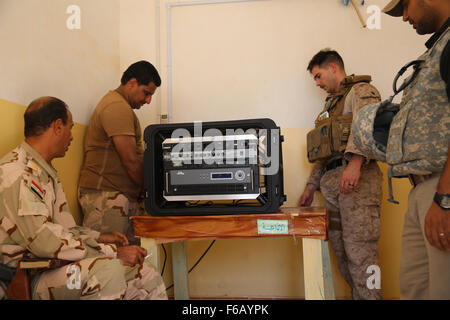 US Marine Staff Sgt Eric Alabiso, Recht, ein militärischer Informationen Operationen Berater mit Task Force Al Asad, hilft ein irakischer Soldat mit der 7. irakische Armee-Division richten Sie ein Radio in einer Box (RIAB) auf Al Asad Air Base, Irak, 28. September 2015. Die RIAB wurde von irakischen Verteidigungsministerium durch den Irak Zug und rüsten Fonds bereitgestellt. Der Fonds wurde von kombiniert Joint Task Force – Betrieb innewohnende lösen (CJTF-OIR), ein Teil der multinationalen Koalition Force gegründet, die hilft, das irakische Militär aufnahmebereiter zur Bekämpfung des islamischen Staates im Irak und der Levante (ISIL) durch die Bereitstellung von tra Stockfoto