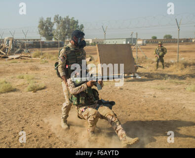 Ein irakischer Soldat zugewiesen, die 71. irakische Armee Brigade Praktiken Schaden/Unfall ziehen während unter Feuer während des Trainings der Patrouille am Camp Taji, Irak, 15. Oktober 2015 zu decken. Irakische Soldaten durchgeführt grundlegende Übungen beim Tragen einer Schutzmaske um die lebhafte Umgebung erstellt durch einen biochemischen Angriff zu simulieren. Teilnahme an dieser Art des Trainings auf dem Camp Taji Partner Kapazitäten Website bereiten die Soldaten zu möglichen biochemischen Angriffen beim Kampf gegen den islamischen Staat im Irak und der Levante. (US Armee-Foto von Spc. William Marlow/freigegeben) Stockfoto