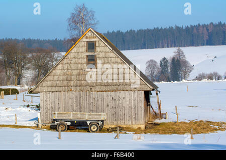 Alte hölzerne Scheune mit einem Wagen in der Winterlandschaft Stockfoto