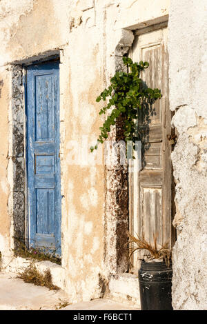 Kykladen, Santorini. Haus Wand, Putz rendering gepatcht und repariert, Türöffnung mit zwei hölzernen Türen, Blau und Braun, beide verwittert, die Farbe blätterte ab. Stockfoto