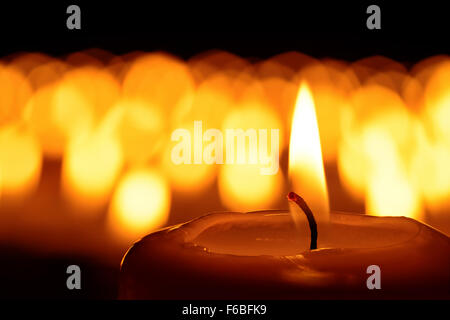 Kerze vor vielen defokussierten Candleflames schafft eine spirituelle Atmosphäre und im Gedenken an Ihren lieben Stockfoto