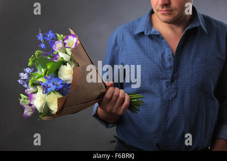 Mann mit einem Blumenstrauß, ein Mann macht einen Vorschlag, eine Frau, ein Liebhaber von Blumen und einem Ring, Liebe Hinweis Hinweis Herrin, in den Blumen versteckt Stockfoto