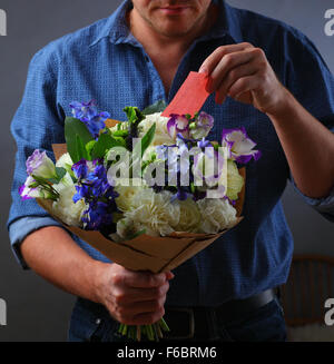 Mann mit einem Blumenstrauß, ein Mann macht einen Vorschlag, eine Frau, ein Liebhaber von Blumen und einem Ring, Liebe Hinweis Hinweis Herrin, in den Blumen versteckt Stockfoto