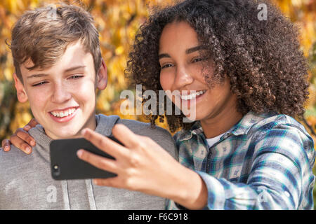 Gemischte Rassen Gruppe zwei glückliche Kinder Jugendliche afroamerikanische Mädchen kaukasischen junge lachen zusammen nehmen Selfie auf Handy Stockfoto