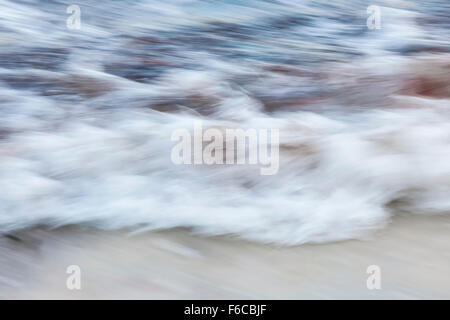 Ozean-Wellen, die am Sandstrand abstrakte, in der Kamera-Bewegung zu verwischen. Stockfoto