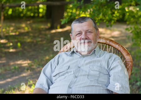 Outdoor Portrait von senior glücklich sitzt auf einem Stuhl im Sommerpark Stockfoto