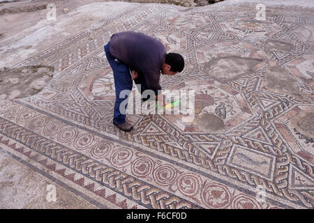 Ein Arbeiter der Israelischen Antikenbehörde reinigt ein 1,700 Jahre altes Mosaik, das während der römischen und byzantinischen Zeit in der israelischen Zentralstadt Lod Israel als Pflaster für den Innenhof einer Villa diente Stockfoto