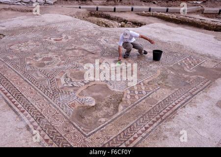 Ein Arbeiter der Israelischen Antikenbehörde reinigt ein 1,700 Jahre altes Mosaik, das während der römischen und byzantinischen Zeit in der israelischen Zentralstadt Lod Israel als Pflaster für den Innenhof einer Villa diente Stockfoto