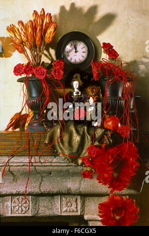 Festliches Silvester, Weihnachten Stilleben mit zwei Puppen und ein Strauß roter Rosen, sowie eine alte Uhr. Hochformat. Stockfoto