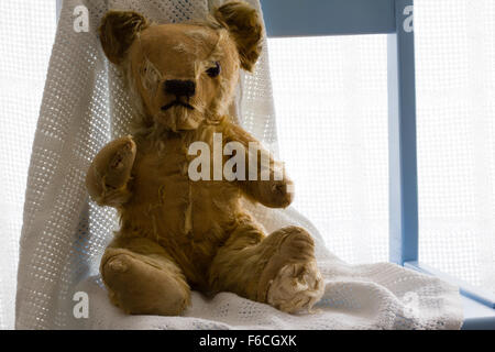 Vintage Teddybär mit einer weißen Decke sitzend auf einem Stuhl blau Kinderzimmer. Weißen Hintergrund. Nahaufnahme, Exemplar, hinterleuchtete Stockfoto