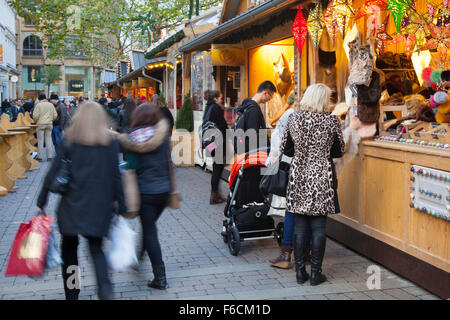 Weihnachtseinkäufer in Manchester UK, festlich dekorierte Holzchalets in St Annes Square. Geschäftiges Stadtzentrum Weihnachtsgeschäfte, Stände & Markthändler. Stockfoto