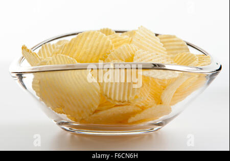 geriffelte Kartoffelchips in Glasschüssel auf weißem Hintergrund jedoch unscharf Stockfoto
