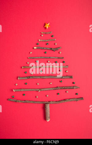 Weihnachtsbaum aus Stöcken auf rotem Hintergrund angeordnet Stockfoto