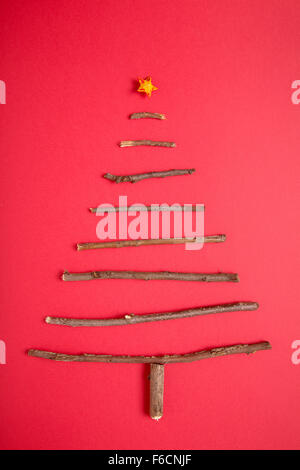 Weihnachtsbaum aus Stöcken auf rotem Hintergrund angeordnet Stockfoto