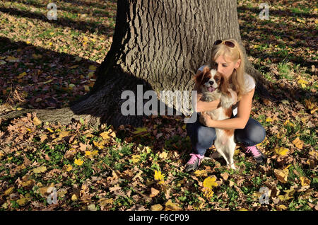 Glückliche Frau umarmt und küsst sie nur gefunden Hund im Wald (Cavalier King Charles Spaniel) Stockfoto