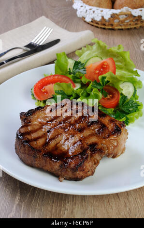 Stück saftiges Schweinesteak vom Grill mit Salat Stockfoto