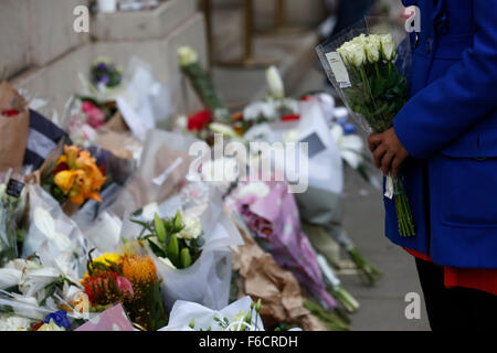 London, UK. 16. November 2015. Eine Frau bereitet sich auf Blumen außerhalb der französischen Botschaft in London, UK, Montag, 16. November 2015 lag.  Eine erhöhte Anzahl von Polizei mit Schusswaffen training nach Paris-Shootings in London zur Verfügung gestellt werden sollen. Bildnachweis: Luke MacGregor/Alamy Live-Nachrichten Stockfoto