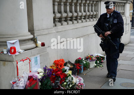 London, UK. 16. November 2015. Ein bewaffneter Polizist patrouilliert in der Nähe von Blumen, für die Toten nach dem shooting in Paris, außerhalb der französischen Botschaft in London, UK, Montag, 16. November 2015 gelegt.  Eine erhöhte Anzahl von Polizei mit Schusswaffen training nach Paris-Shootings in London zur Verfügung gestellt werden sollen. Bildnachweis: Luke MacGregor/Alamy Live-Nachrichten Stockfoto