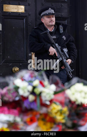 London, UK. 16. November 2015. Ein bewaffneter Polizist patrouilliert in der Nähe von Blumen, für die Toten nach dem shooting in Paris, außerhalb der französischen Botschaft in London, UK, Montag, 16. November 2015 gelegt.  Eine erhöhte Anzahl von Polizei mit Schusswaffen training nach Paris-Shootings in London zur Verfügung gestellt werden sollen. Bildnachweis: Luke MacGregor/Alamy Live-Nachrichten Stockfoto