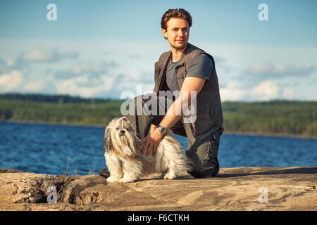 Junger Mann Tourist mit Shih-Tzu Hund am Seeufer. Stockfoto