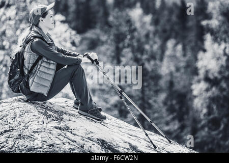 Junge Frau Touristen sitzen auf Berggipfel und beiseite auf Wald. Farben schwarz und weiß. Stockfoto