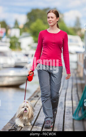 Junge Frau mit Shih-Tzu Hundewiesen auf Stadtkai mit Booten. Stockfoto