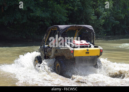 Der Mann auf dem ATV kreuzt einen Stream. Touristischen Spaziergänge auf einem cross-country Gelände. Stockfoto