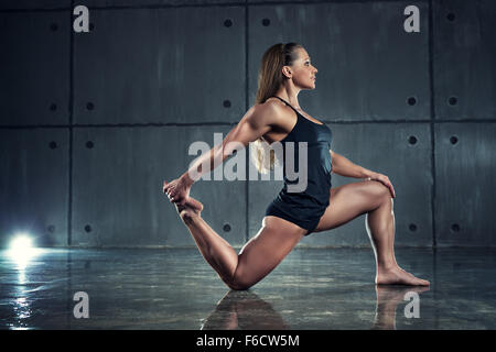 Starke Frau Bodybuilder auf Wand Hintergrund dehnen. Stockfoto