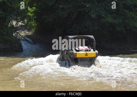 Der Mann auf dem ATV kreuzt einen Stream. Touristischen Spaziergänge auf einem cross-country Gelände. Stockfoto