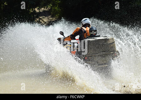 Der Mann auf dem ATV kreuzt einen Stream. Touristischen Spaziergänge auf einem cross-country Gelände. Stockfoto