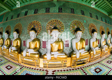 SAGAING, Myanmar – die OoHminThoneSel Pagode, hoch auf einem Hügel in Sagaing, verfügt über eine lange, geschwungene Nische, die mit Dutzenden von Statuen des Buddha gesäumt ist. Nach kürzlich stattfindenden Renovierungen und Modernisierungen, die von Spendern ermöglicht wurden, ist die Pagode mit farbenfrohen Fliesenmosaiken und frischen, hellen Farben verziert. Stockfoto