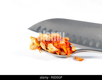 Einen Löffel Butternut-Kürbis-Samen und ein Messer vor einem weißen Hintergrund Stockfoto
