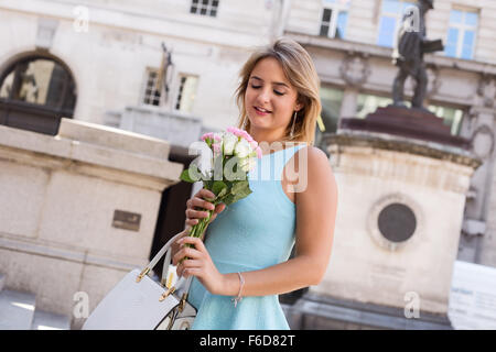 junge Frau in der Stadt hält einen Strauß Rosen Stockfoto