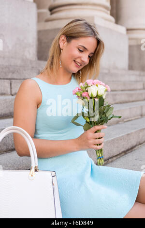 junge Frau sitzt auf einer Stufe mit einem Blumenstrauß Stockfoto